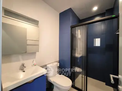 Modern bathroom with sleek blue tiles and glass shower enclosure