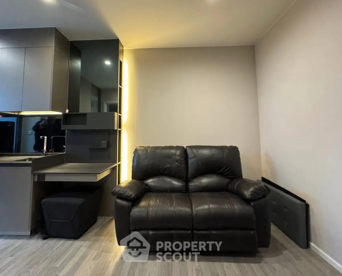 Modern living room with sleek leather sofa and stylish kitchen area