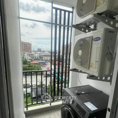 Compact balcony with city view, featuring air conditioning units and washing machine.