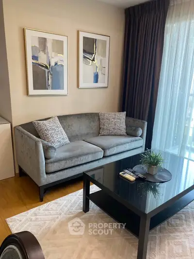 Elegant living room with modern sofa, abstract art, and glass coffee table in a cozy apartment.
