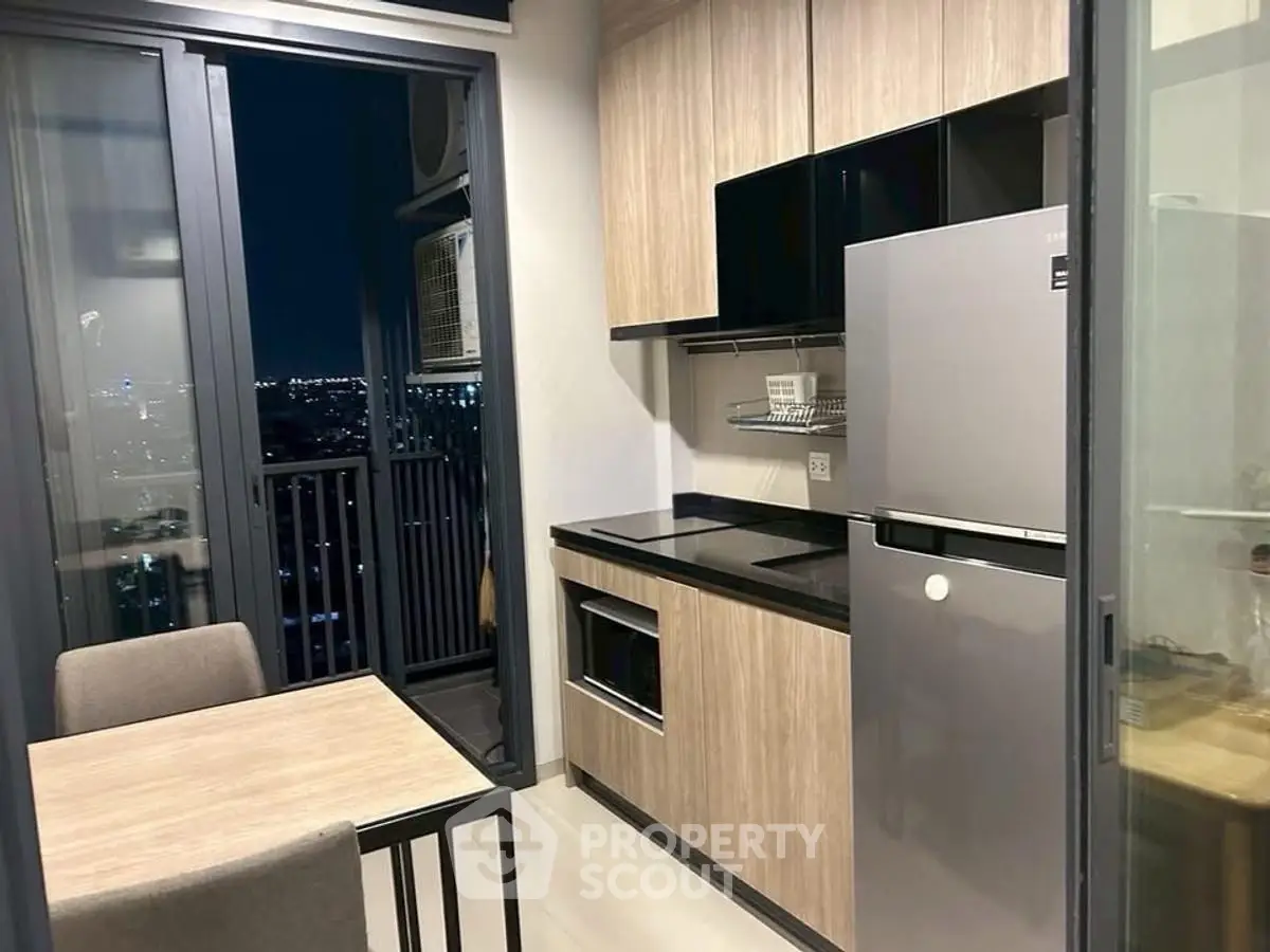 Modern kitchen with sleek cabinets and city view from balcony at night.