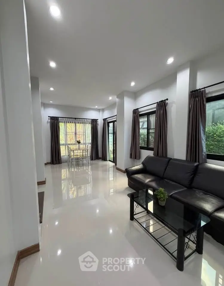 Spacious modern living room with sleek black sofa and large windows
