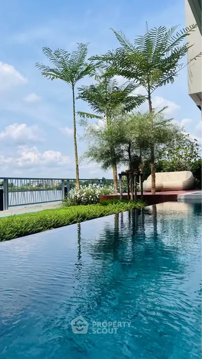 Luxurious poolside with lush greenery and serene water view, perfect for relaxation and leisure.