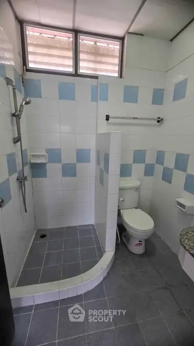 Spacious bathroom with modern shower and tiled walls in a well-lit setting.
