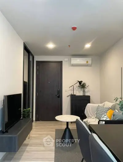 Modern living room with stylish decor and cozy seating area, featuring a sleek TV setup and air conditioning.
