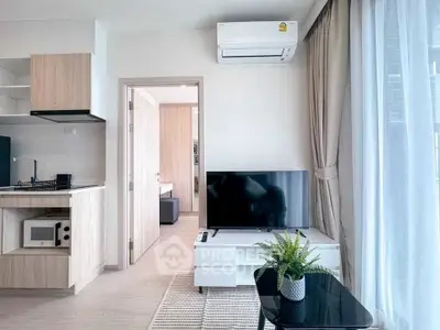 Modern living room with sleek TV setup and open kitchen design in a stylish apartment.