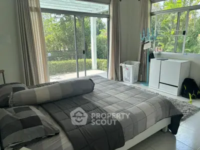 Spacious bedroom with large windows and garden view, featuring modern decor and ample natural light.