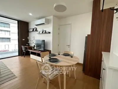 Modern living room with dining area, featuring sleek furniture and natural light.