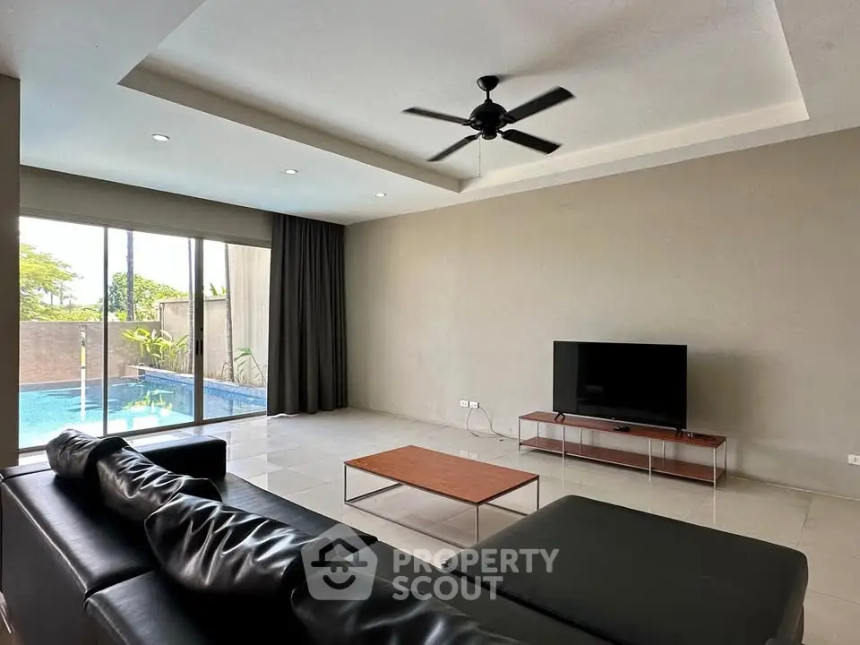 Spacious modern living room with pool view and sleek black furniture.