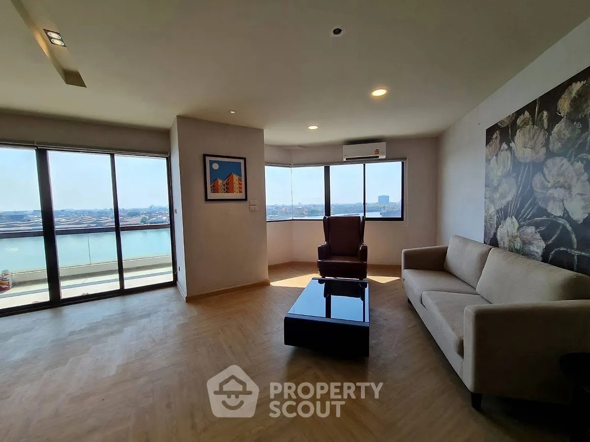 Spacious living room with stunning river view and modern furnishings.