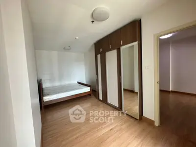 Spacious bedroom with wooden flooring and built-in wardrobe in modern apartment
