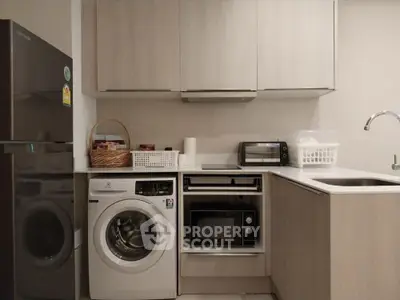 Modern kitchen with appliances including washing machine and microwave, sleek cabinetry, and compact design.