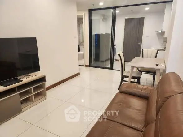 Modern living room with leather sofa and dining area in open layout apartment.