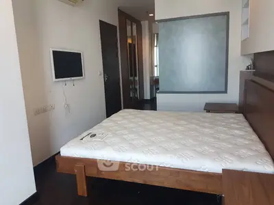 Spacious bedroom with modern decor and wall-mounted TV in a stylish apartment.