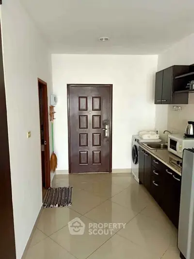 Compact kitchen with washing machine and microwave in modern apartment