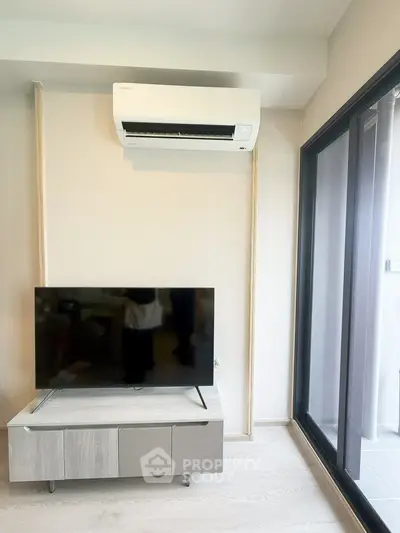 Modern living room with air conditioning and TV, featuring sleek design and balcony access.