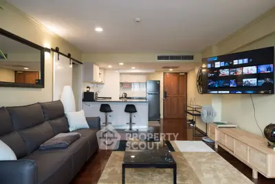 Modern living room with open kitchen and large TV, perfect for entertainment.