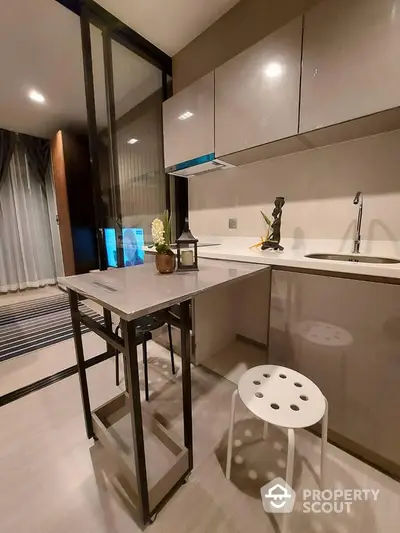 Modern kitchen with sleek cabinetry and compact dining area in stylish apartment