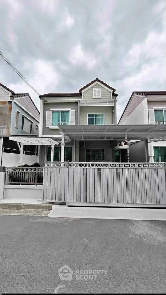 Charming two-story house with modern facade and gated entrance in a serene neighborhood.