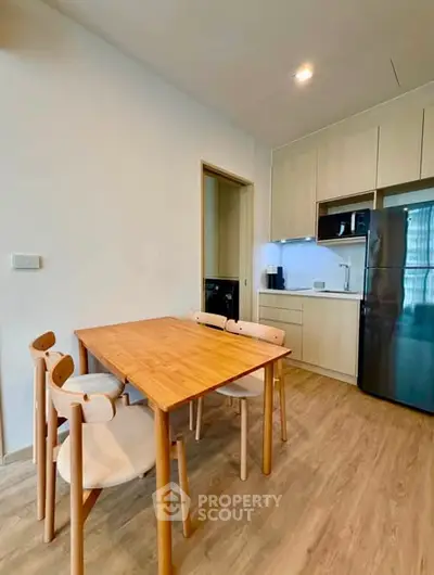 Modern kitchen with wooden dining table and sleek appliances in a cozy apartment setting.