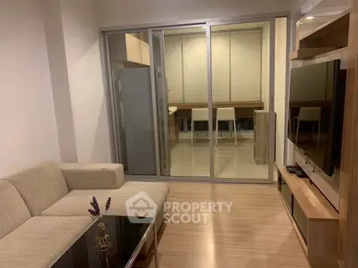 Modern living room with sleek furniture and glass partition leading to a stylish kitchen.