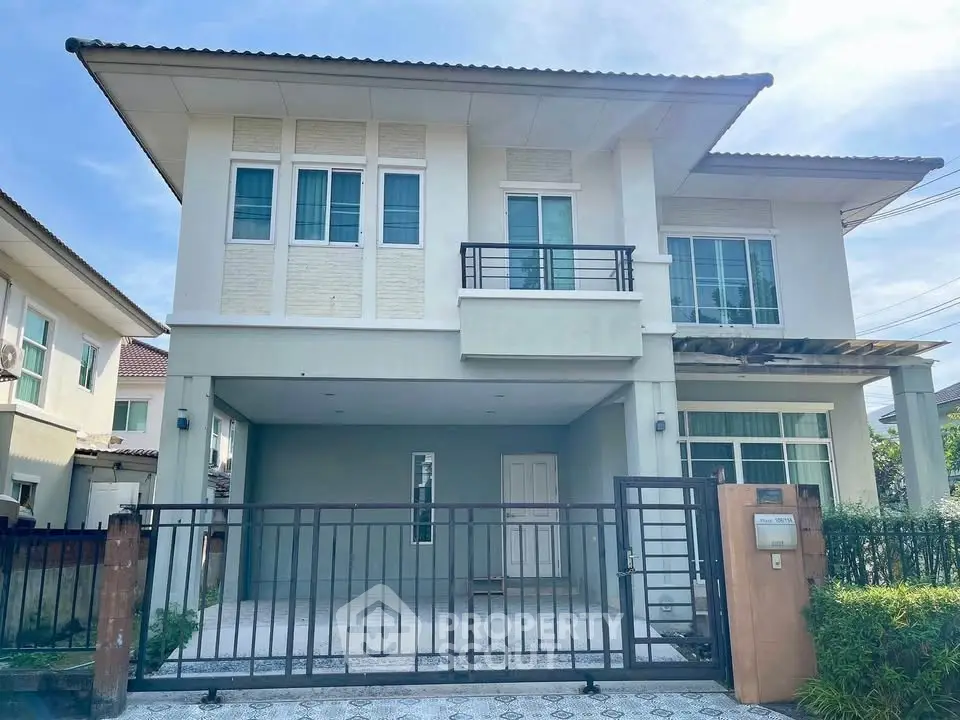 Modern two-story house with gated driveway and contemporary design.