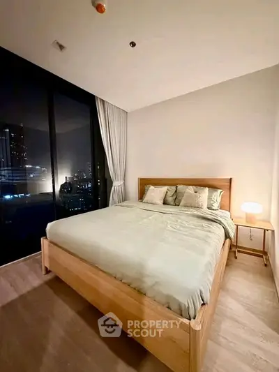 Modern bedroom with city view, featuring a cozy bed and ambient lighting for a serene atmosphere.