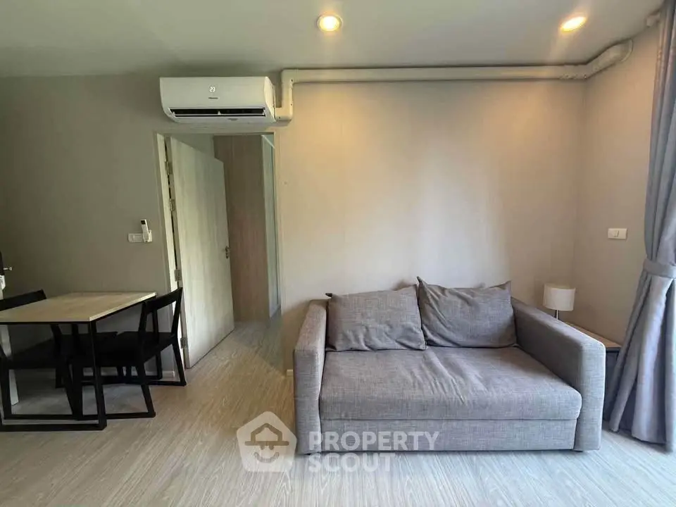 Modern living room with cozy gray sofa and dining area in stylish apartment.