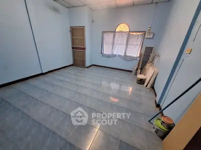 Spacious empty room with blue tiled floor and window, ideal for customization.