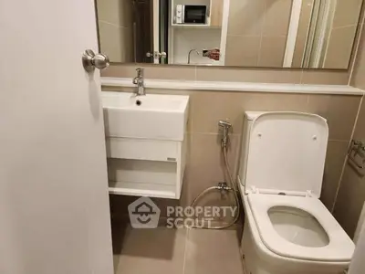Modern bathroom with sleek fixtures and neutral tones, featuring a compact sink and toilet.