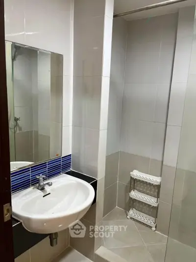 Modern bathroom with sleek sink and spacious shower area in contemporary apartment.