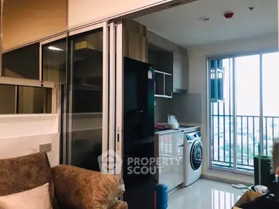Modern apartment with open kitchen and laundry area, featuring a washing machine and balcony view.