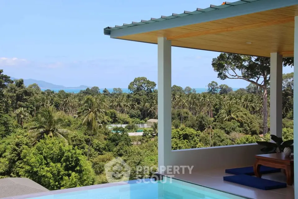 Luxurious tropical villa with infinity pool and stunning panoramic views of lush greenery and ocean.