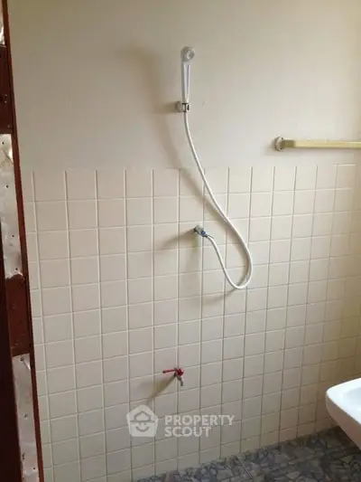 Minimalist bathroom with tiled walls and shower head, ideal for compact spaces.