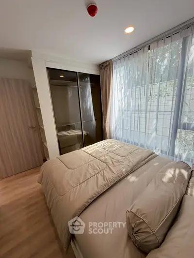 Cozy bedroom with large window and mirrored wardrobe in modern apartment