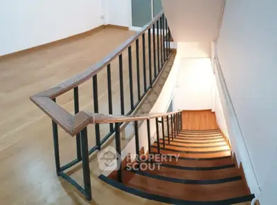 Elegant wooden staircase with sleek metal railing in modern home interior.