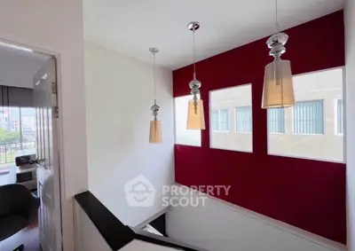 Stylish staircase with modern pendant lights and bold red accent wall in a contemporary home.