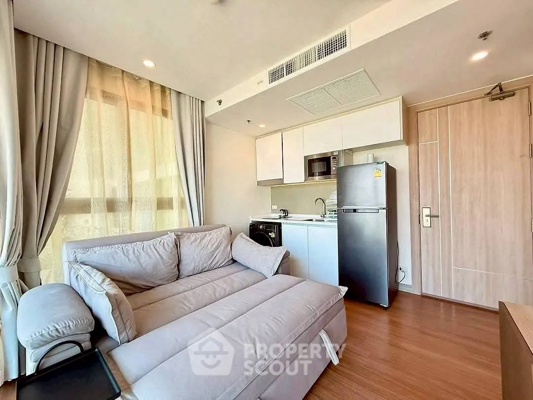 Modern living room with cozy sofa and compact kitchen in open layout apartment.