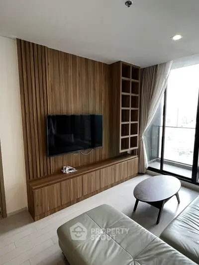 Modern living room with sleek wooden paneling and TV, featuring a cozy seating area and balcony view.