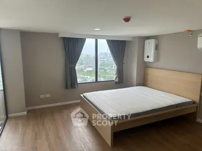 Spacious bedroom with large window offering stunning city views in modern apartment.
