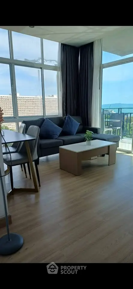 Spacious living room with large windows offering stunning city and sea views, modern furniture, and elegant decor.