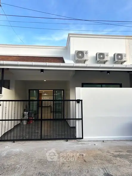 Modern single-story house with gated entrance and air conditioning units.