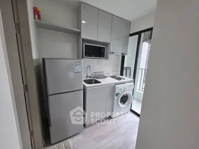 Modern compact kitchen with appliances and balcony access in urban apartment