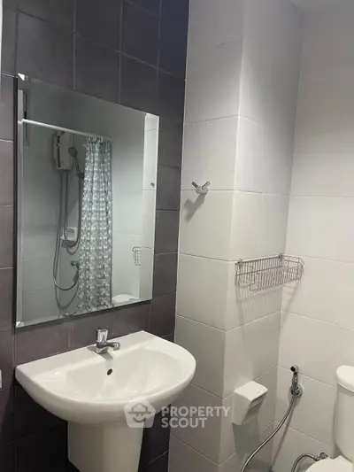 Modern bathroom with sleek sink and shower area, featuring stylish tile design.