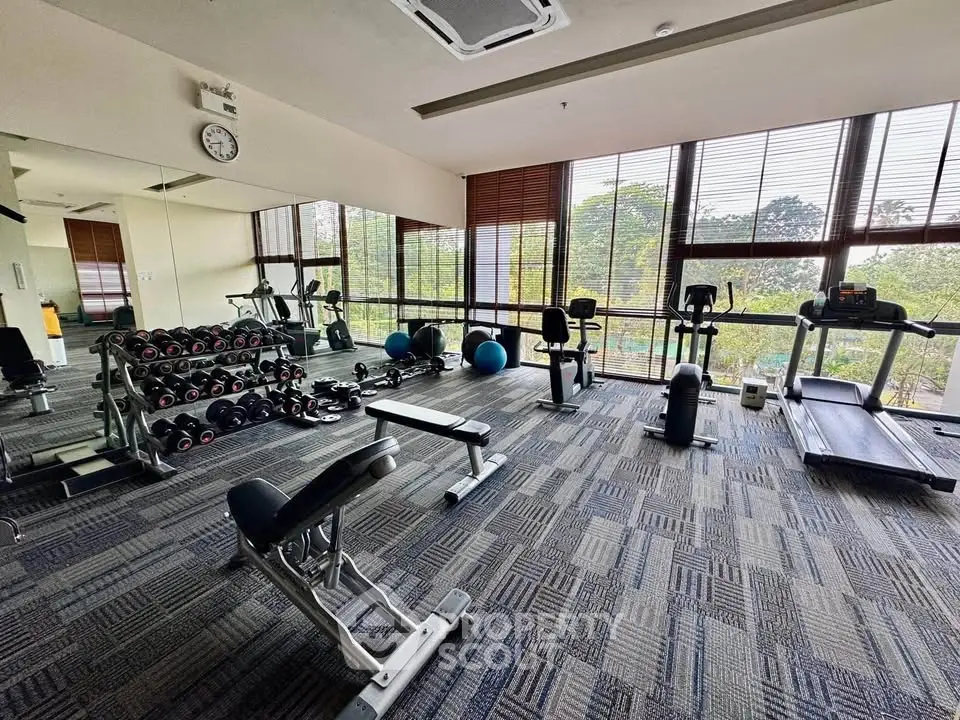 Spacious gym with modern equipment and large windows offering scenic views.