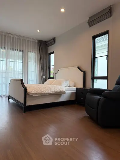 Spacious bedroom with modern decor and large windows for natural light.