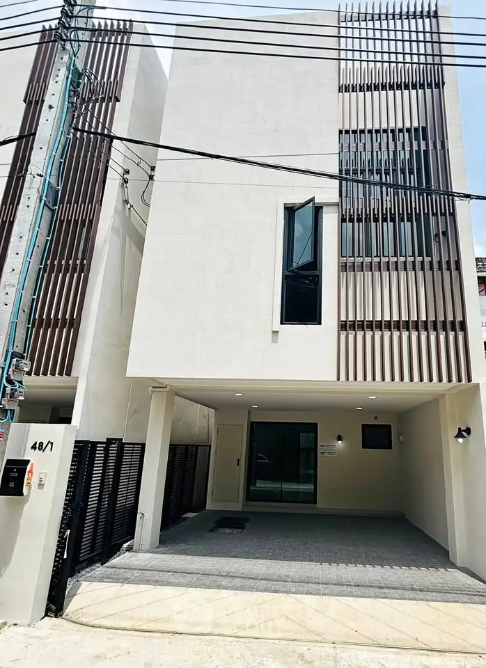 Modern minimalist townhouse exterior with sleek facade and spacious driveway.