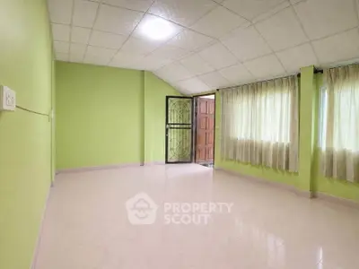 Spacious green-walled room with large windows and open door, perfect for customization.