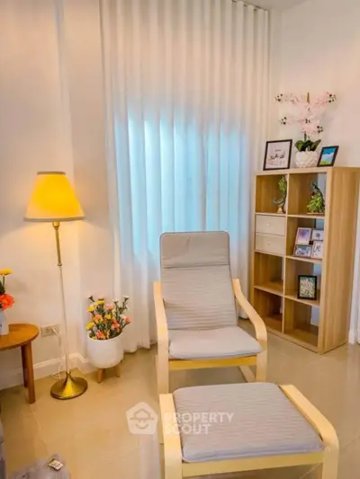Cozy living room corner with modern chair, lamp, and decorative shelving.