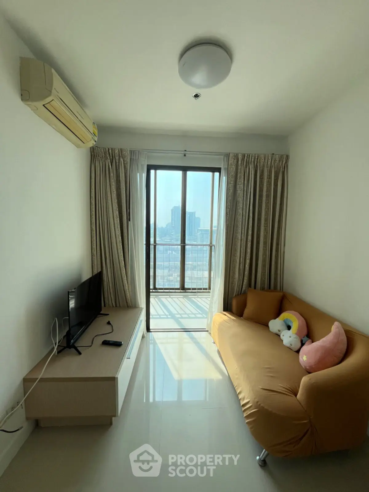 Bright living room with cozy sofa and city view balcony